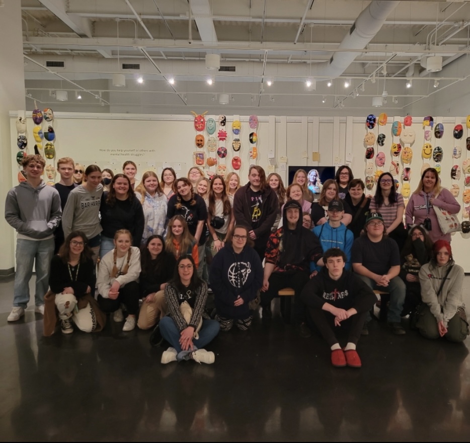 Art students pose on the top floor of the museum where their masks are displayed. 