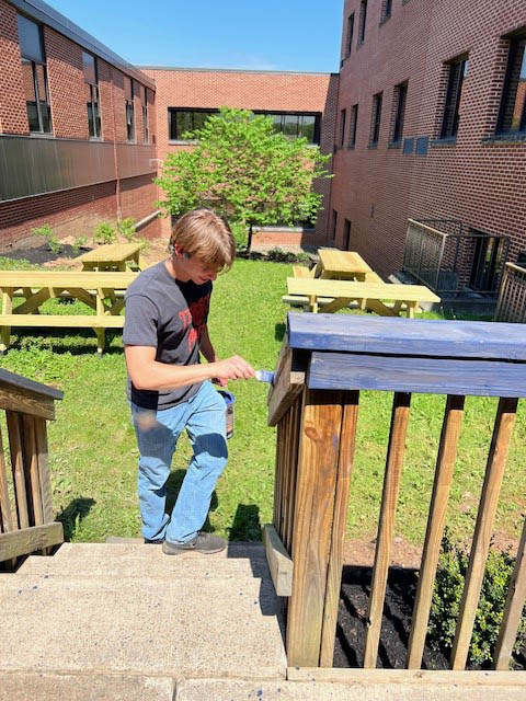 Senior Seth Prosser paints the courtyard during Keystone week.  