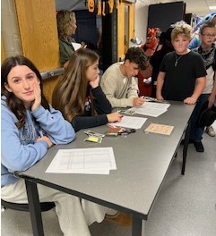 Members of the Senior Class check-in middle school students after school for the Halloween dance. The group split proceeds with the Travel Club.
